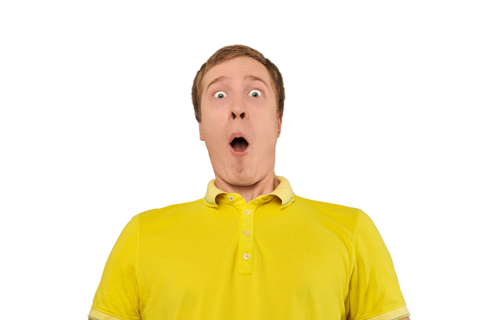 Surprised young guy with funny face in yellow T-shirt, white isolated background. Shocked amazed face of young man with wide open mouth in yellow T-shirt on white background. Portrait of excited man