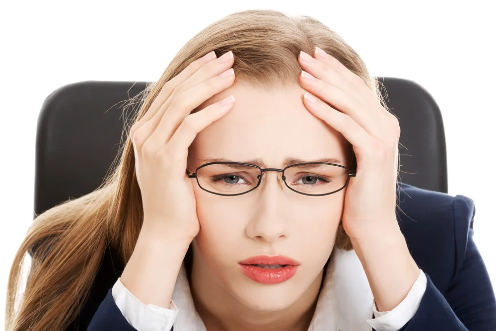Worried, sad business woman sitting by the table. Isolated on white.