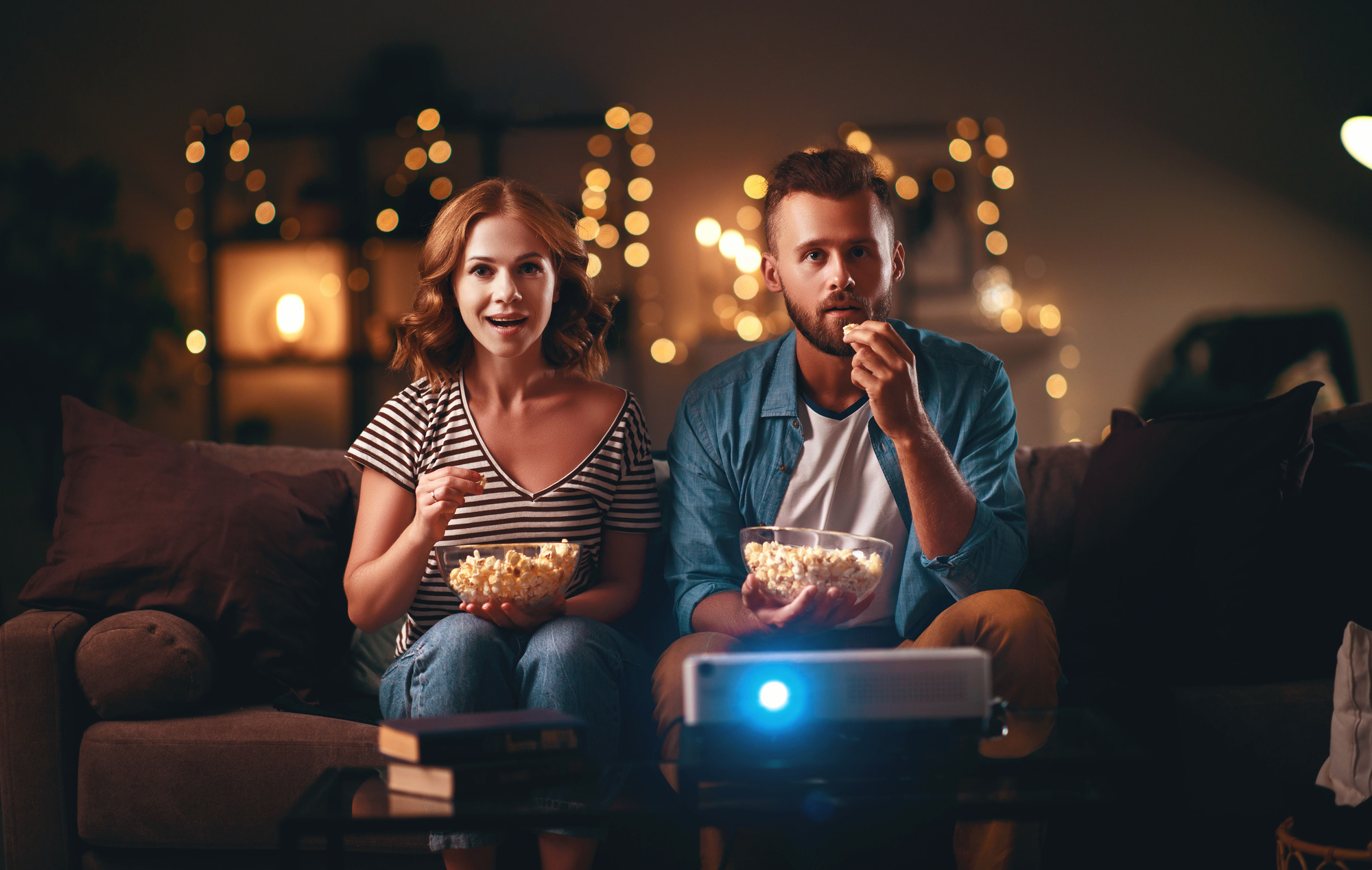 Family couple watching television projector at home on the sofa