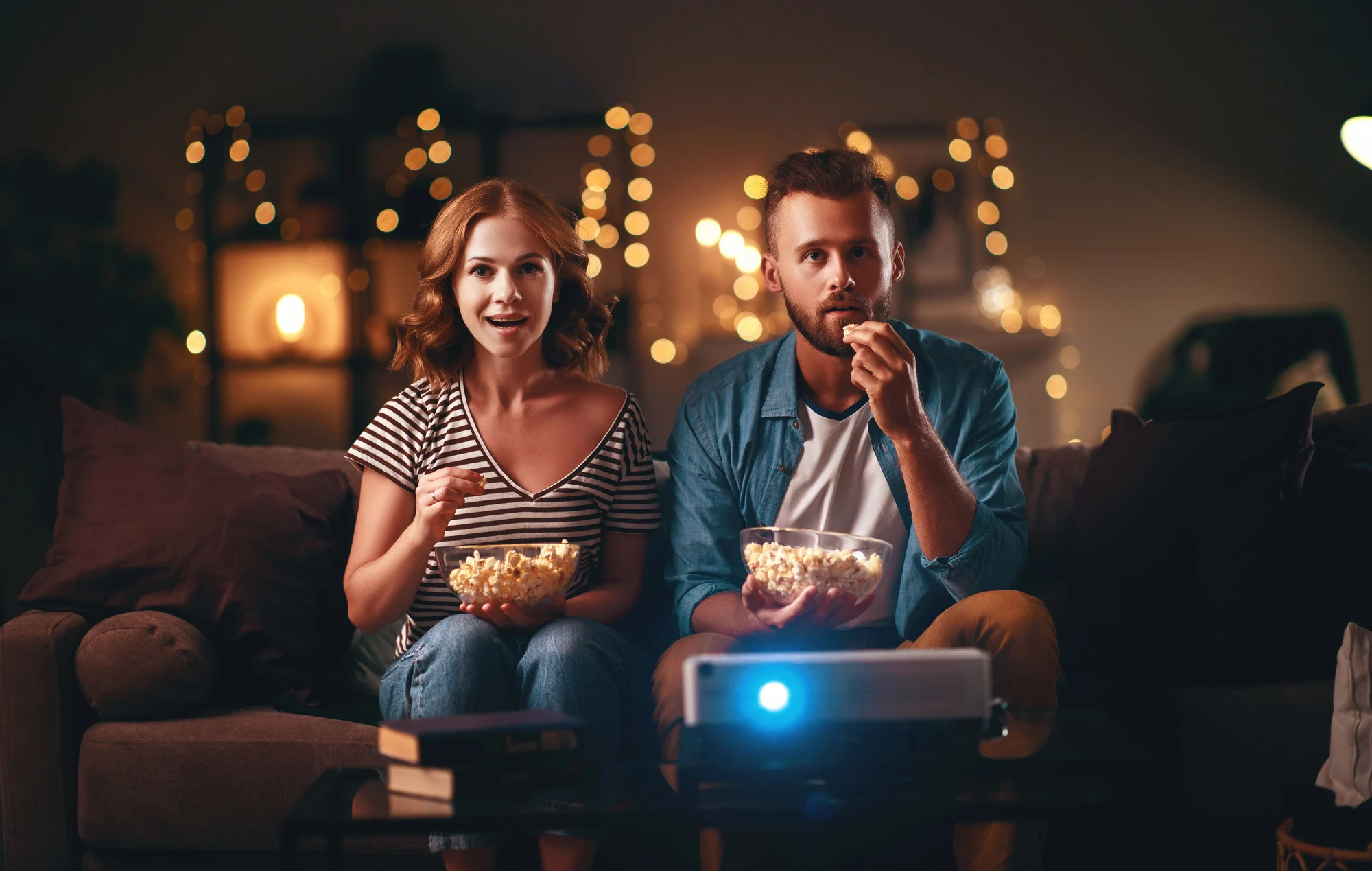 Family couple watching television projector at home on the sofa