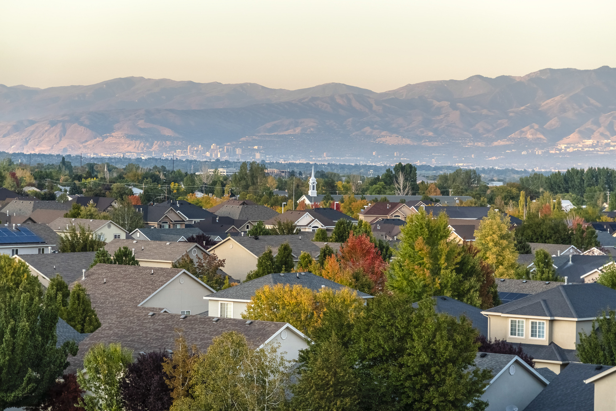 Rooftop view of a suburb of Salt Lake City, Utah. Rooftop view of a suburb of Salt Lake City, Utah with houses nestled amongst green trees and a distant mountain range