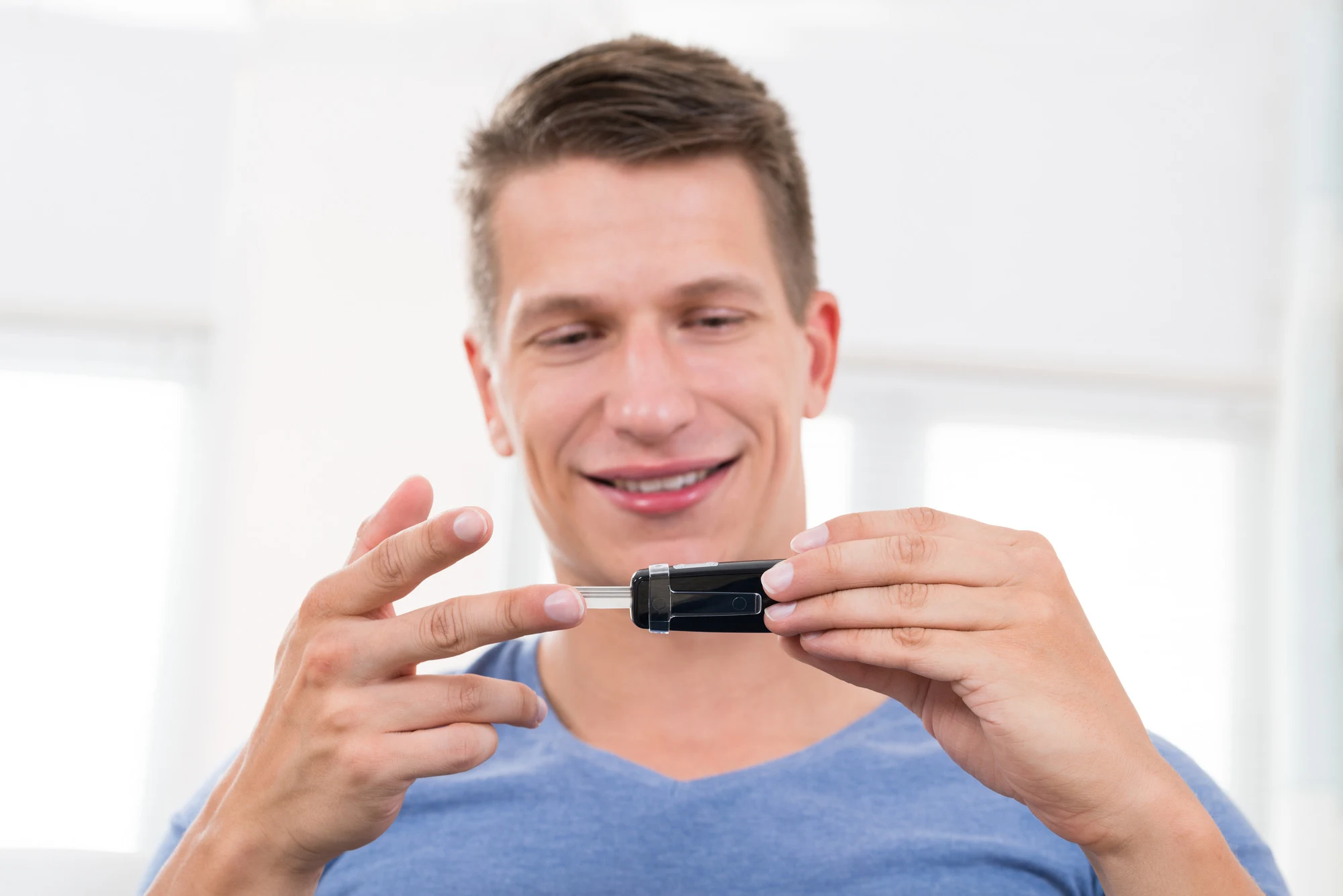 Close-up Of Young Happy Man Checking Blood Sugar Level With Glucometer