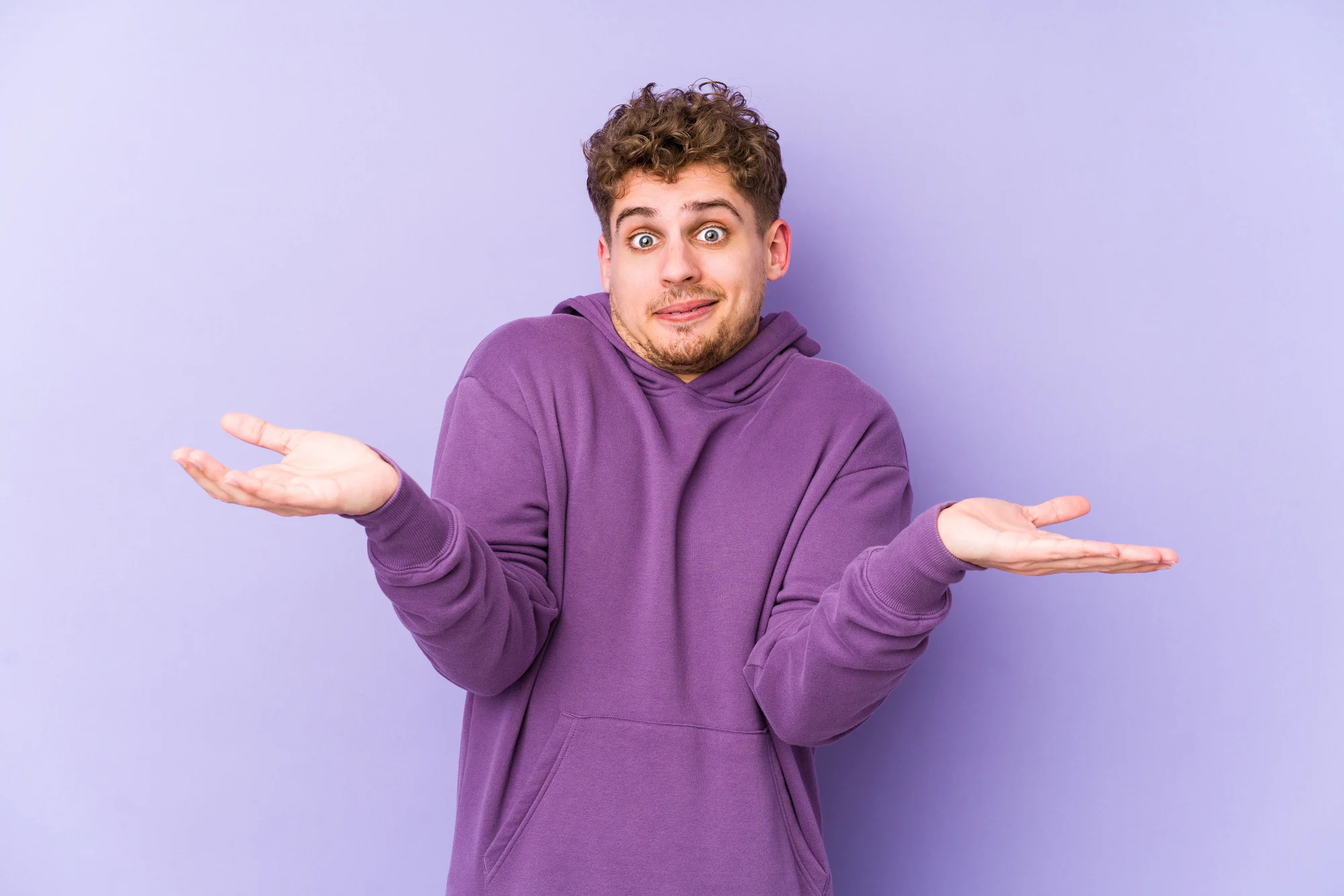 Young blond curly hair caucasian man isolated doubting and shrugging shoulders in questioning gesture.