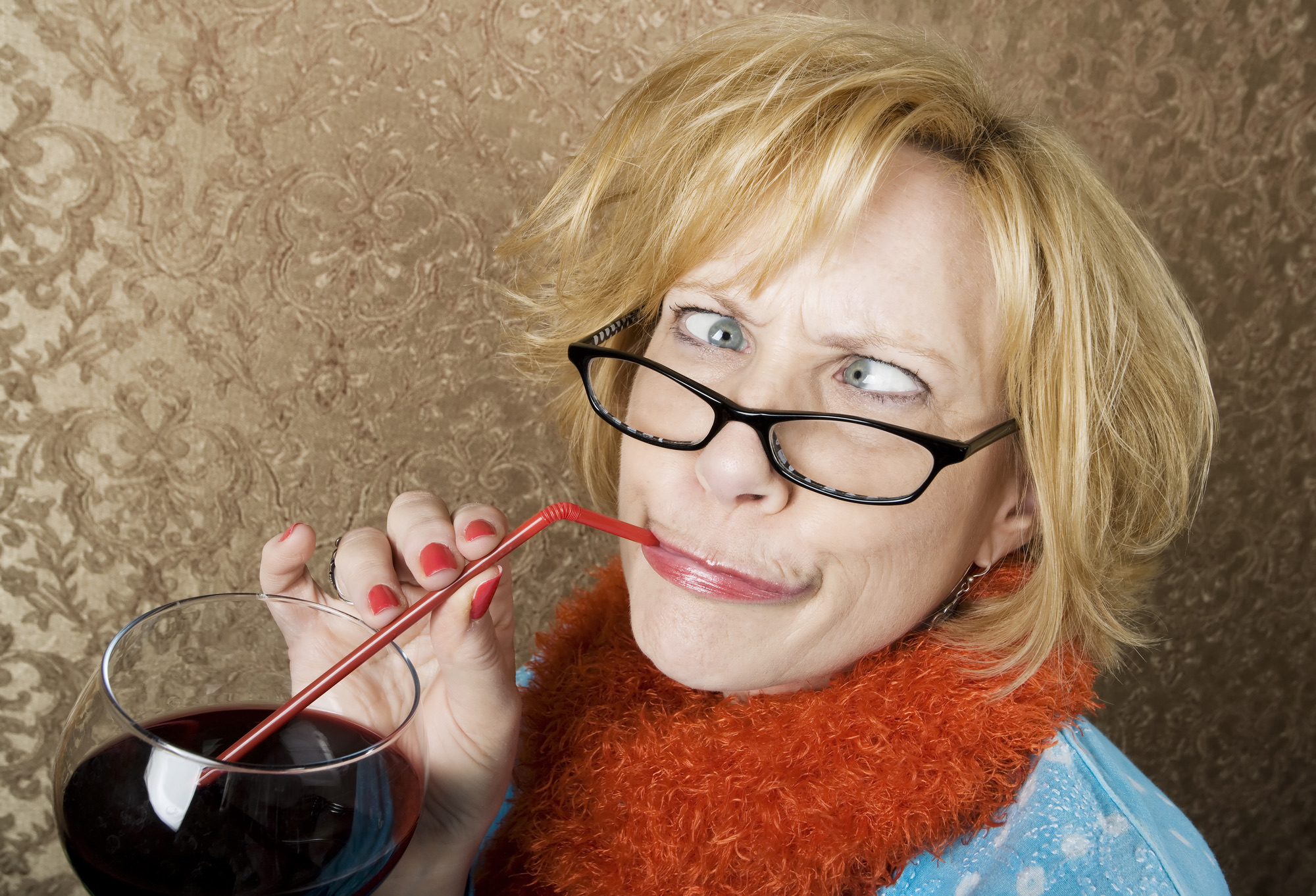 Crazy woman with crossed eyes drinking wine through a straw
