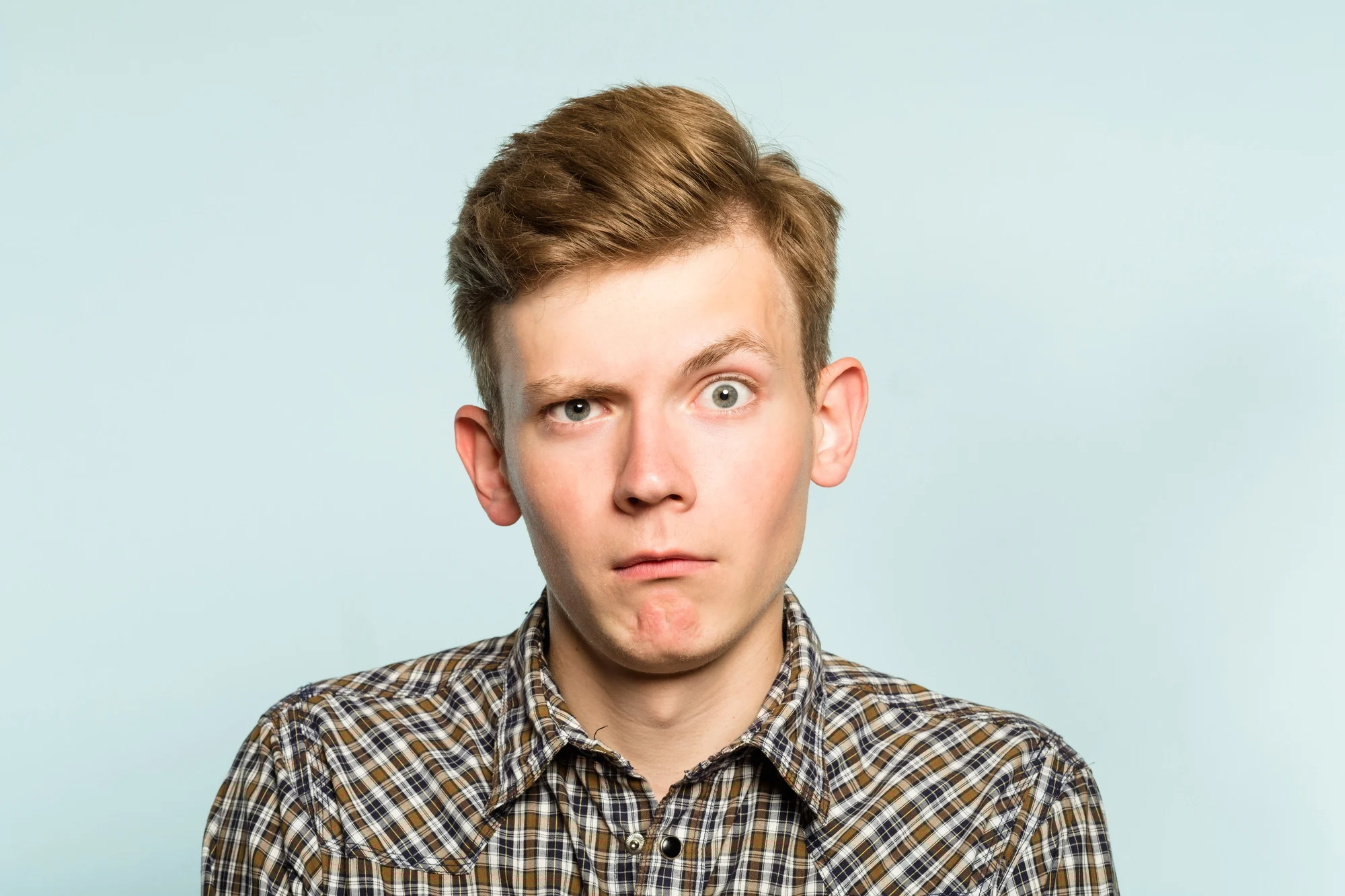 puzzled confused bewildered shocked amazed man. comical reaction. portrait of a young guy on light background. emotion facial expression and feelings concept.