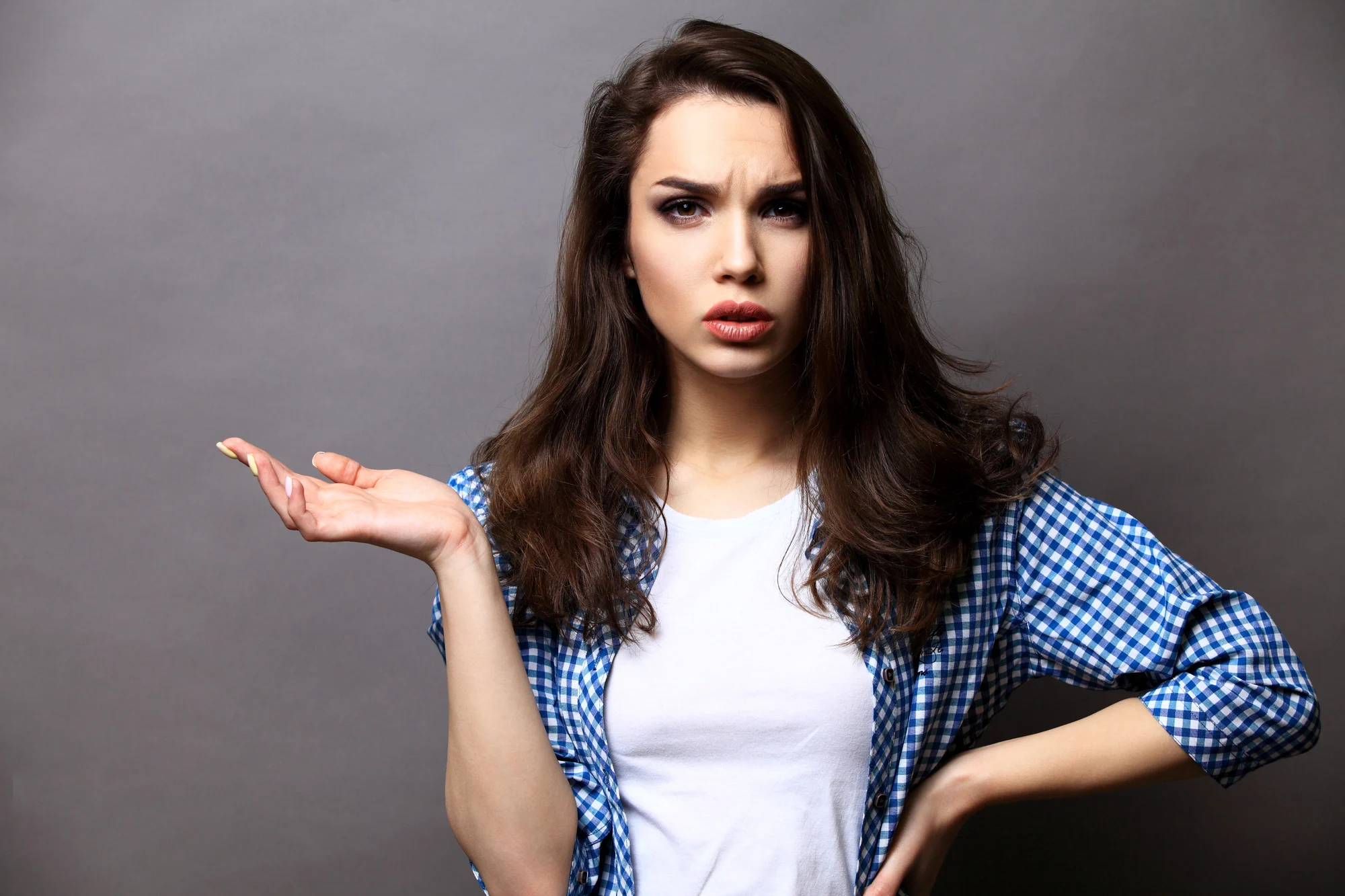 Smiling woman in gesture of asking over gray background.