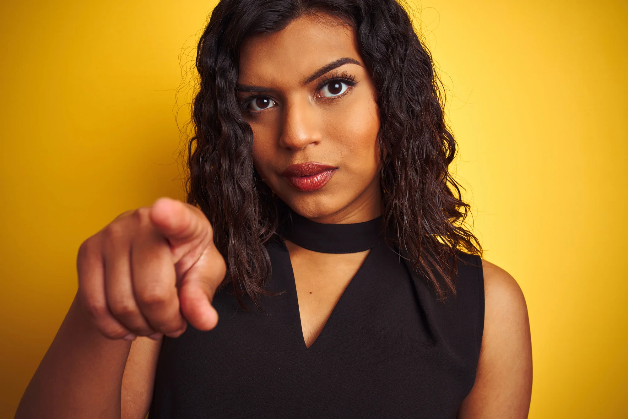 Transsexual transgender woman wearing black t-shirt over isolated yellow background pointing with finger to the camera and to you, hand sign, positive and confident gesture from the front
