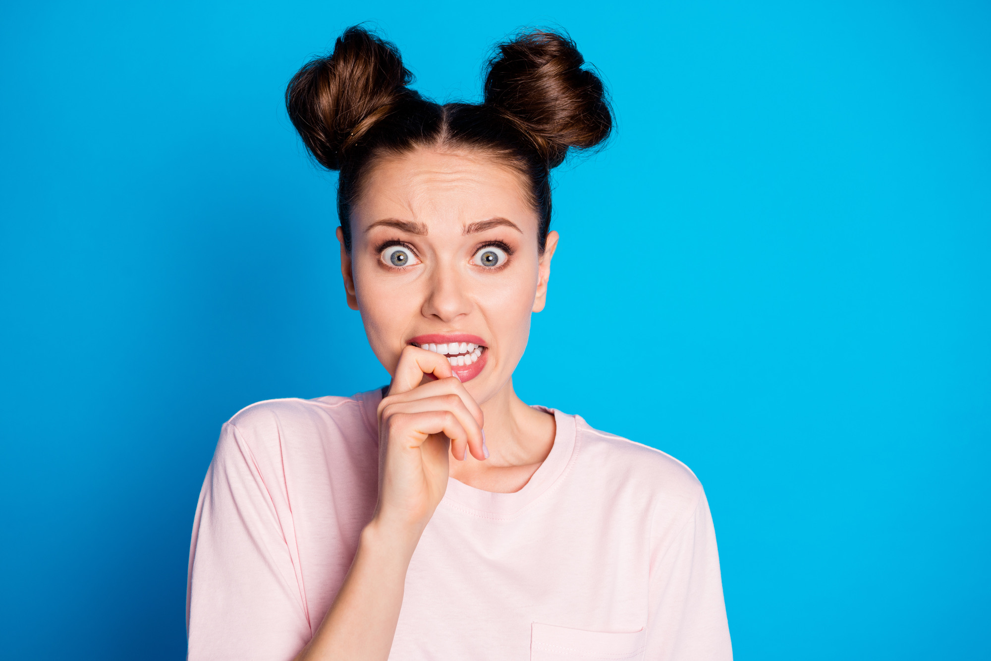 Close-up portrait of her she nice attractive lovely pretty worried terrified, scared brown-haired girl biting finger phobia isolated on bright vivid shine vibrant blue color background.