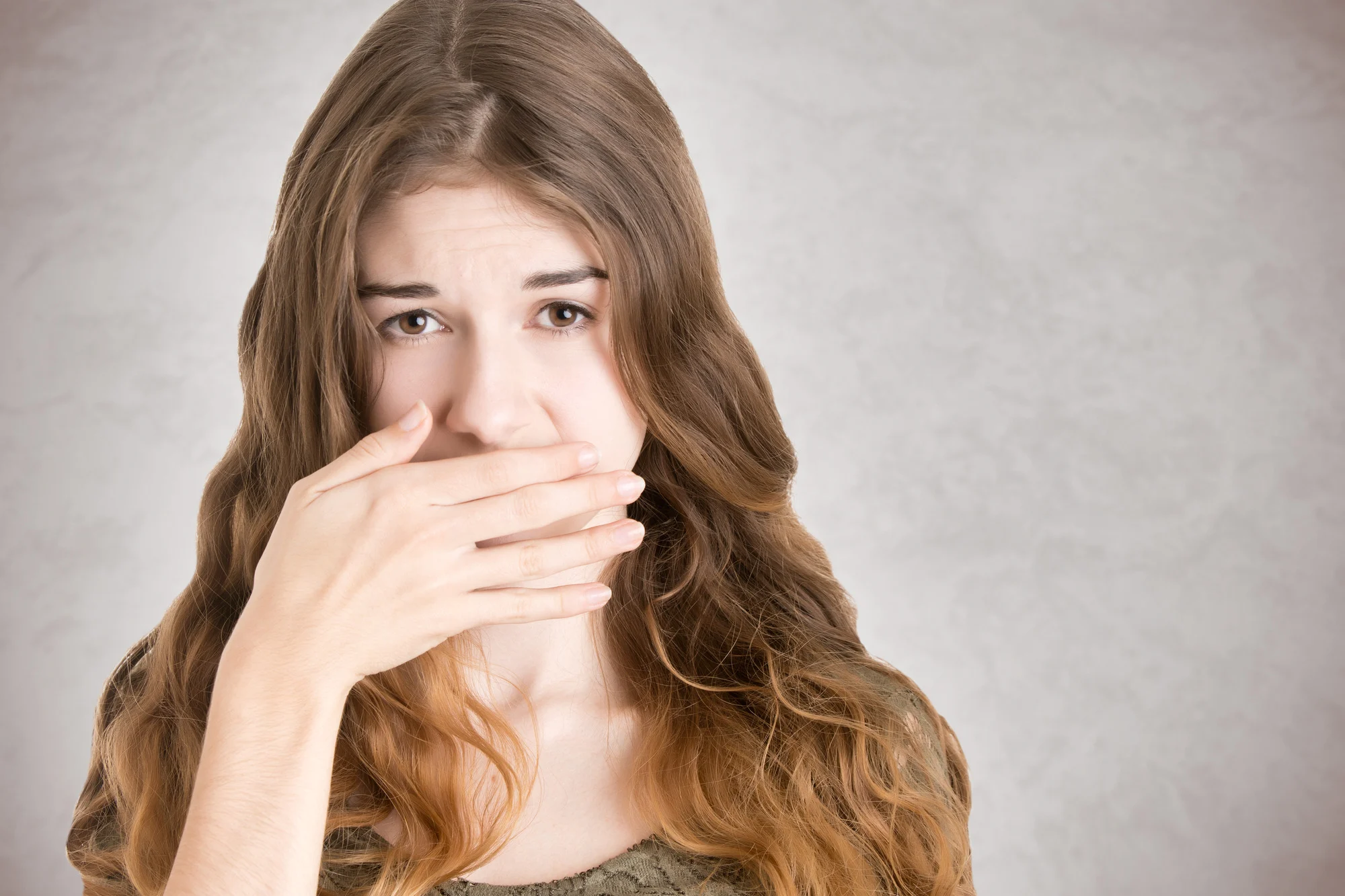 Female covering her mouth with her hand, isolated in white