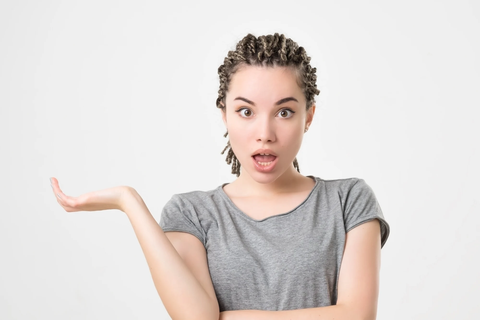 Portrait of caucasian girl with braids having doubtful and indecisive face expression. Confused young female posing isolated at white wall