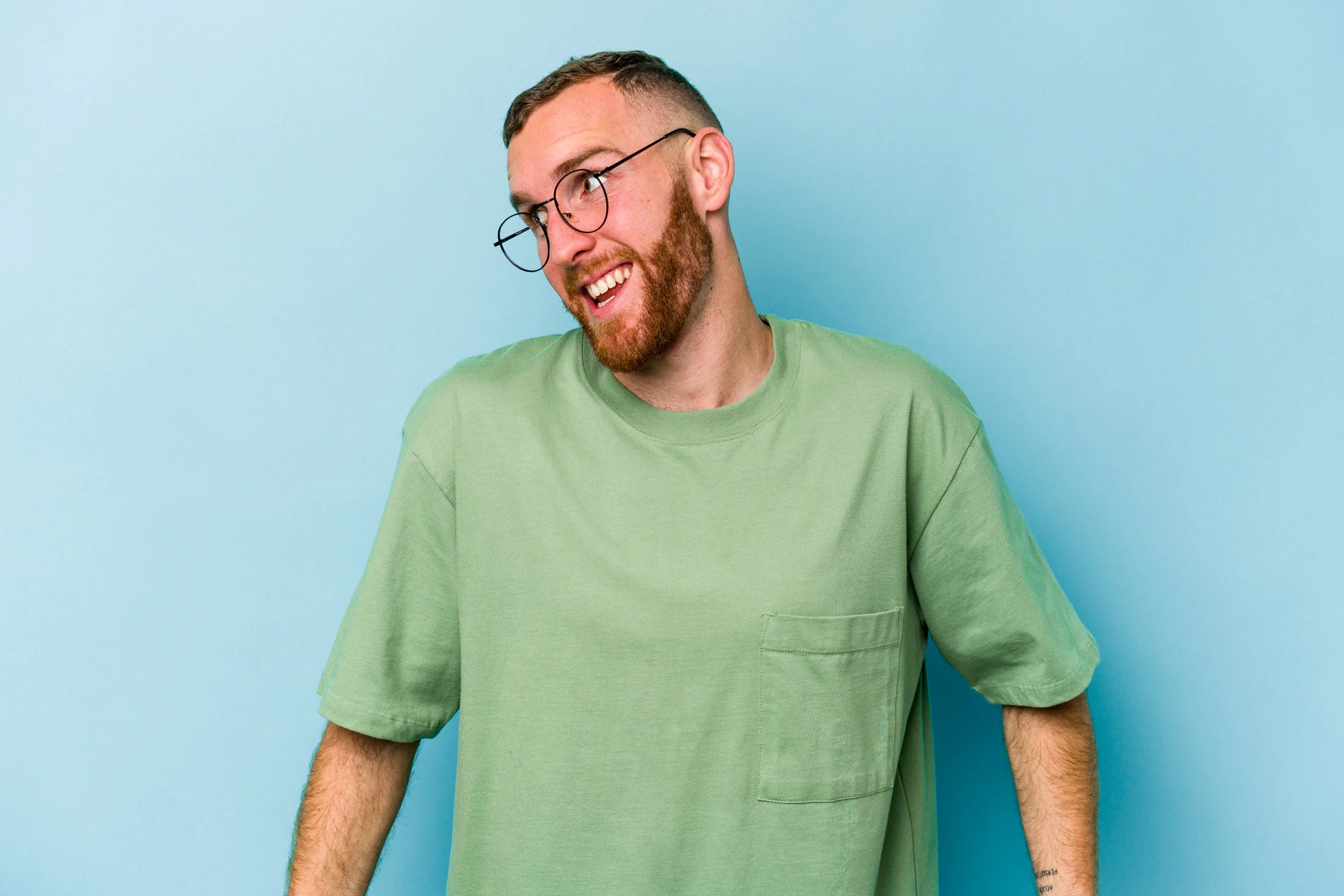 Young caucasian man isolated on blue background laughs and closes eyes, feels relaxed and happy.