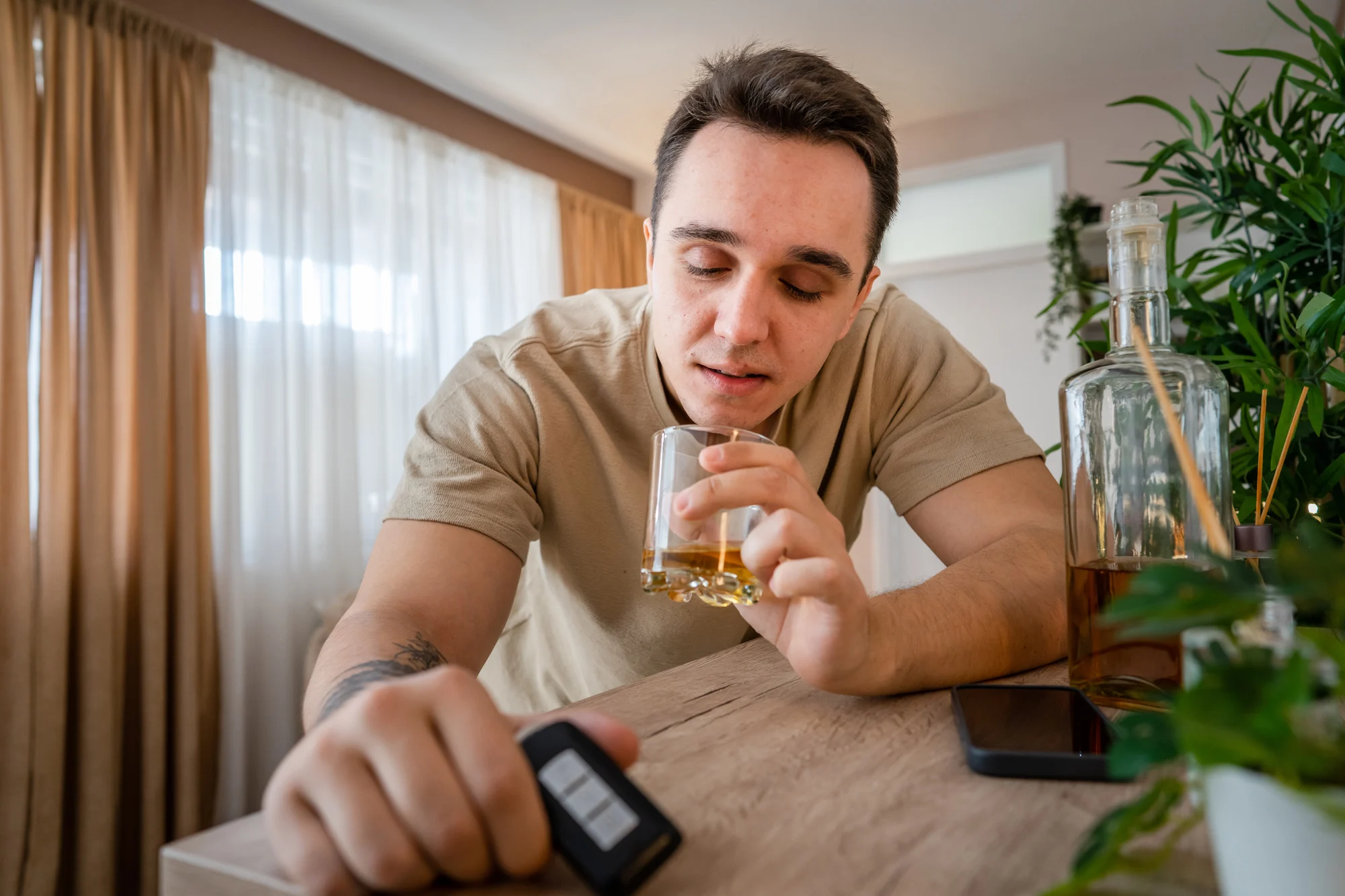 one man sit at home with bottle of liquor drink whiskey drunk alcoholic Alcohol abuse, addiction and man depression concept drink and drive copy space hold car keys