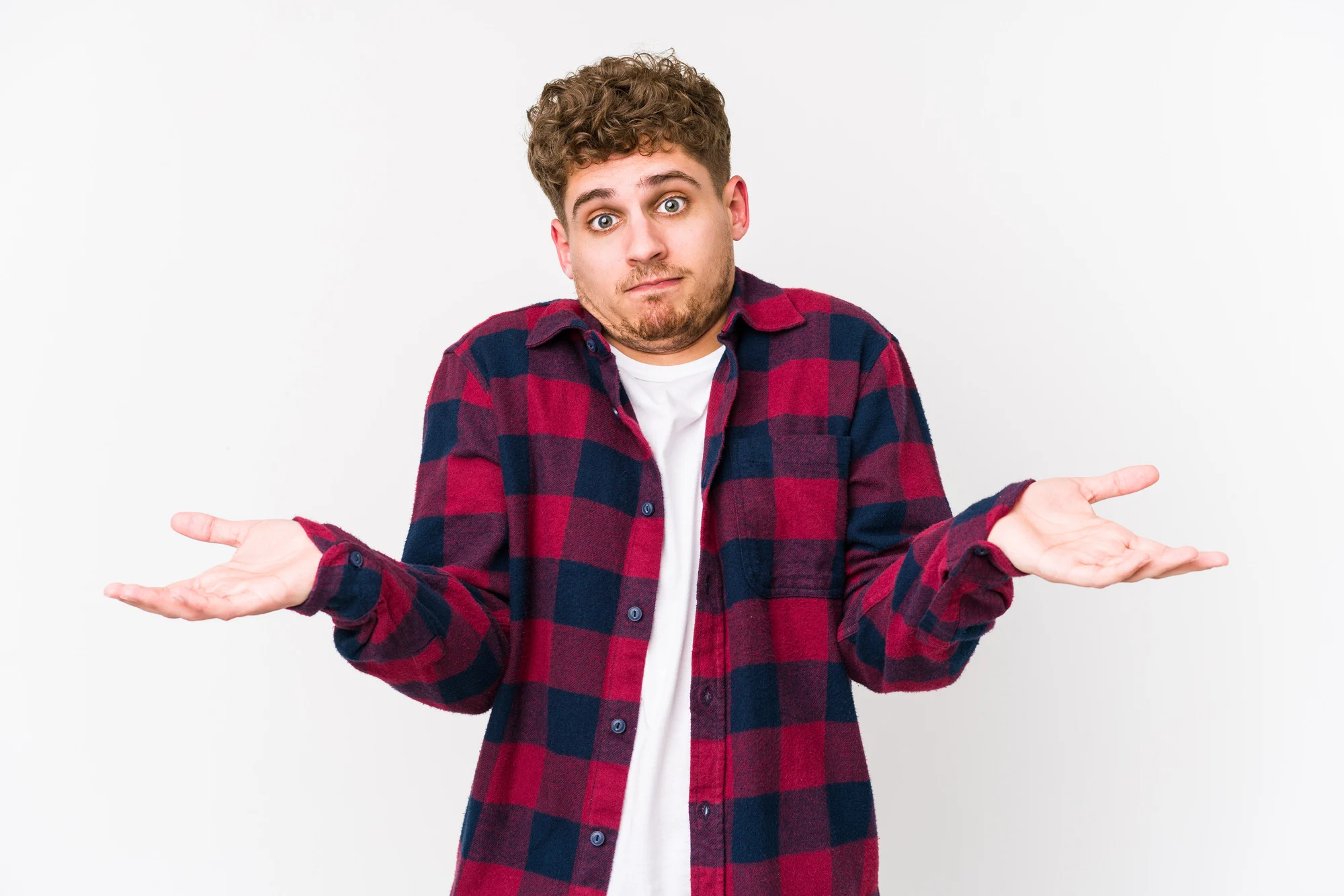 Young blond curly hair caucasian man isolated doubting and shrugging shoulders in questioning gesture.