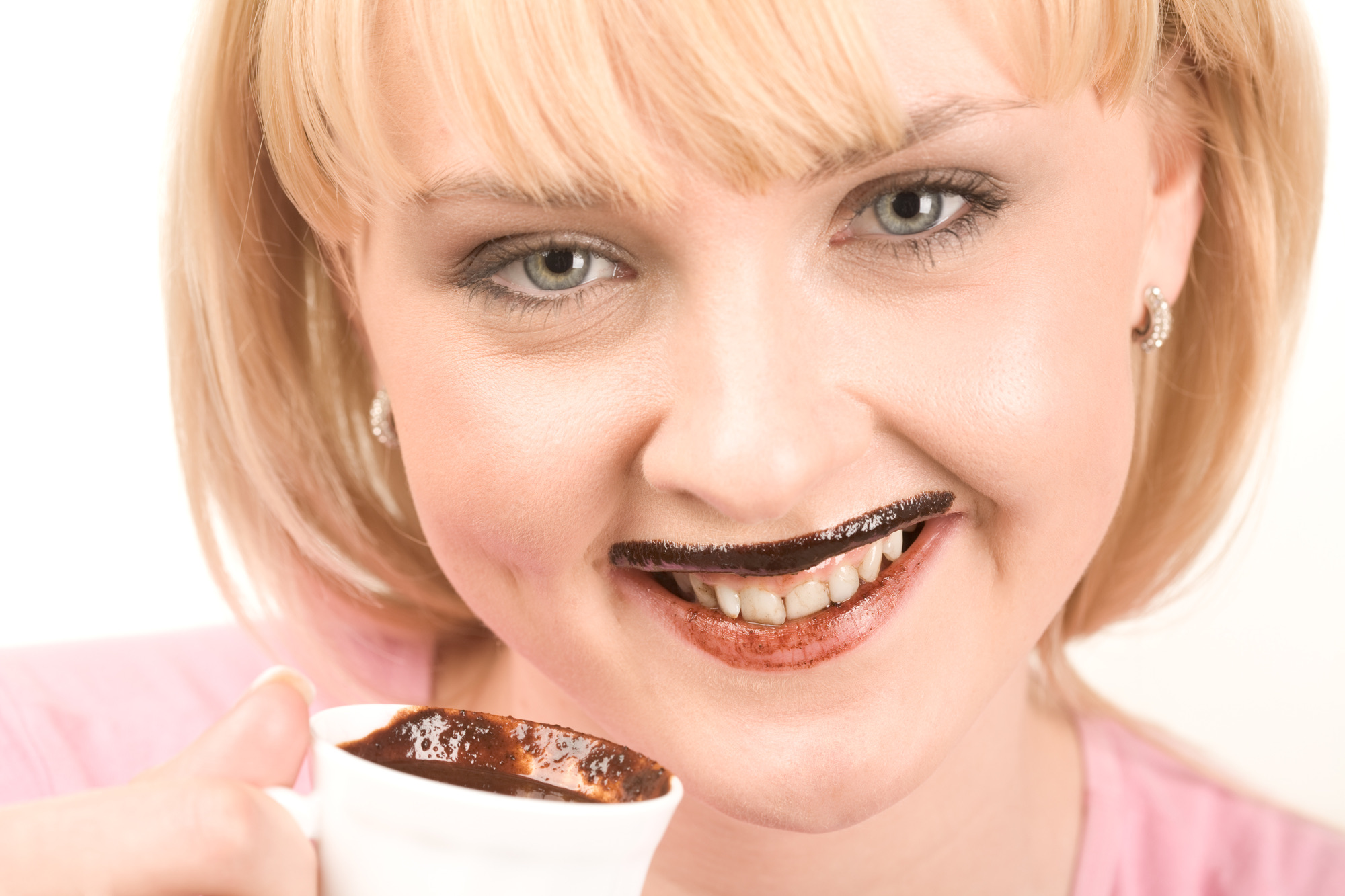 Close-up of pretty girl enjoying hot chocolate and smiling at camera