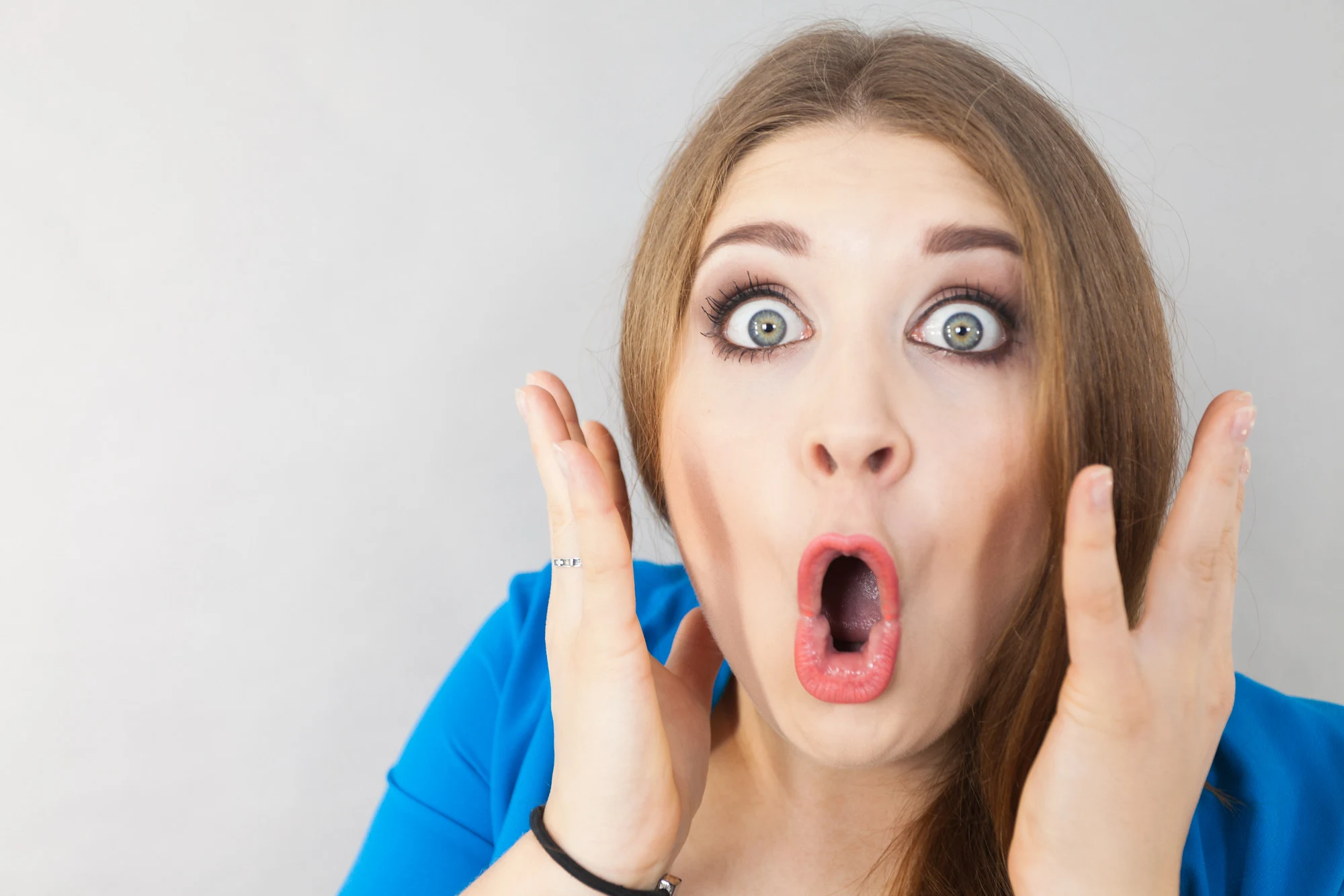 Close up on funny woman expression. Female lady being surprised shocked having wide opened eyes.