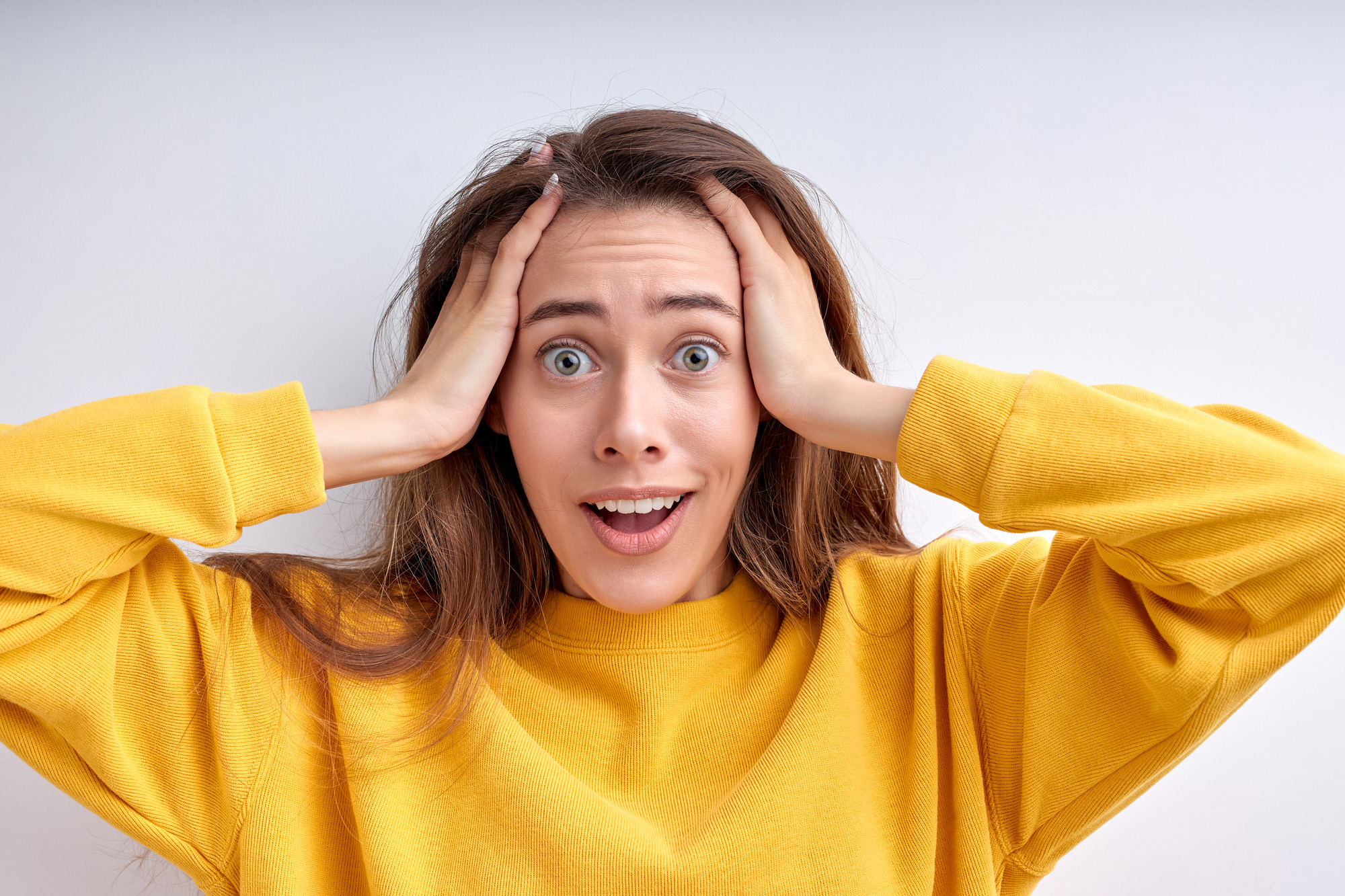 Emotional woman in panic grabs head and looks frustrated at camera realizes big failure poses worried dressed casually isolated over white background. Negative human feelings. People lifestyle