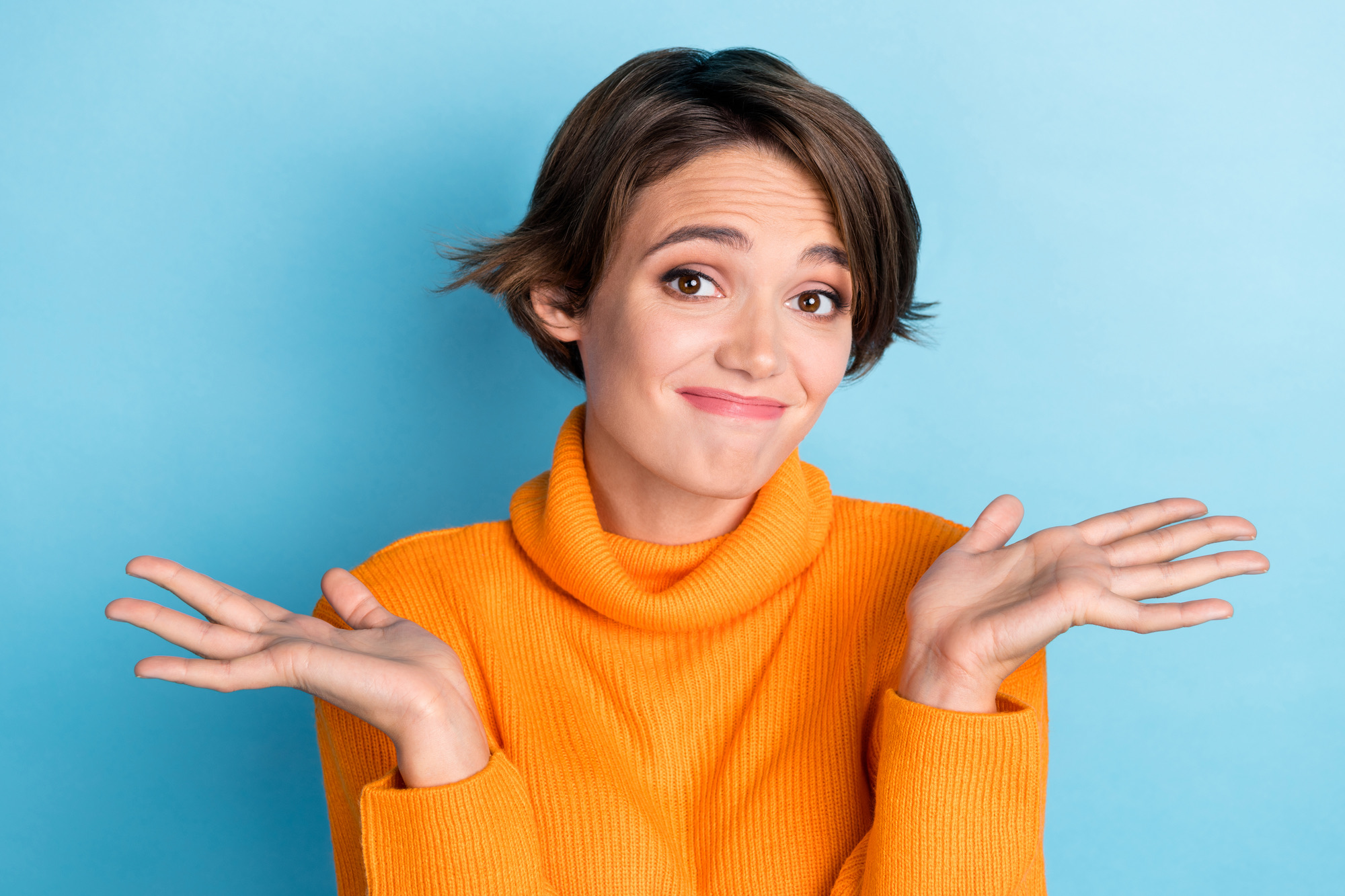 Photo portrait of lovely young lady sorry forget shrug shoulders cute wear trendy orange clothes isolated on blue color background.