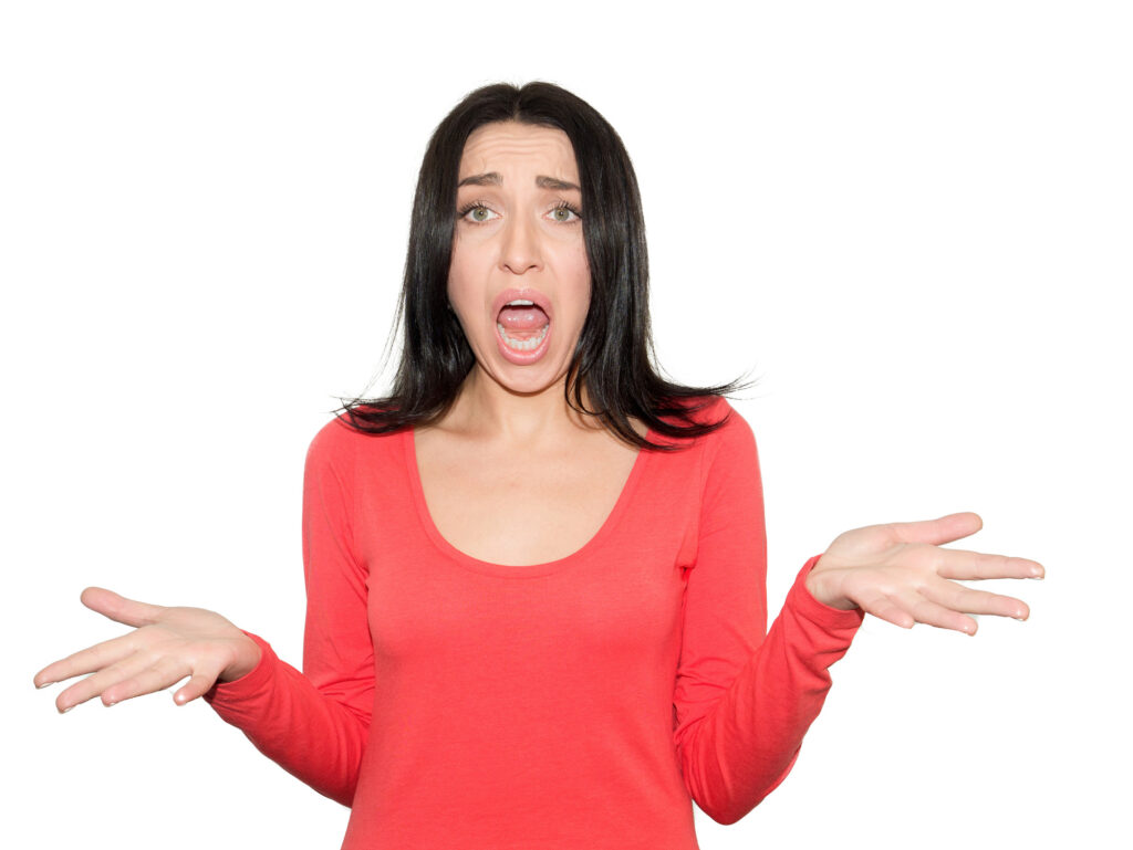 portrait of a young brunette woman , wearing a pink sweater , with an irritated expression, hands in the air, isolated on white background. Negative human emotions