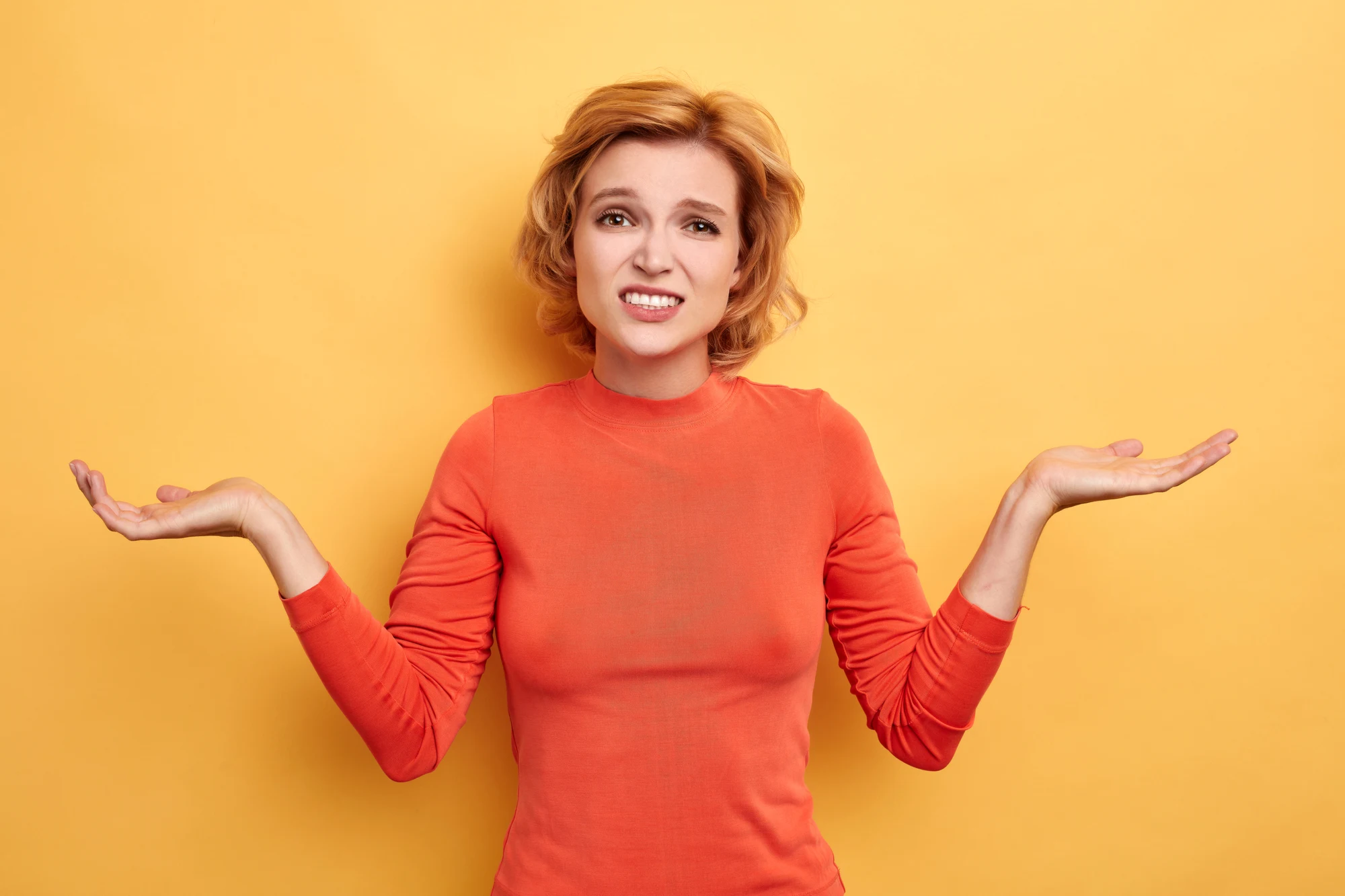 puzzled beautiful fair-haired woman shrugs shoulders with open palms. she cannot find the sloution of problem,puzzlement. feeling and emotion