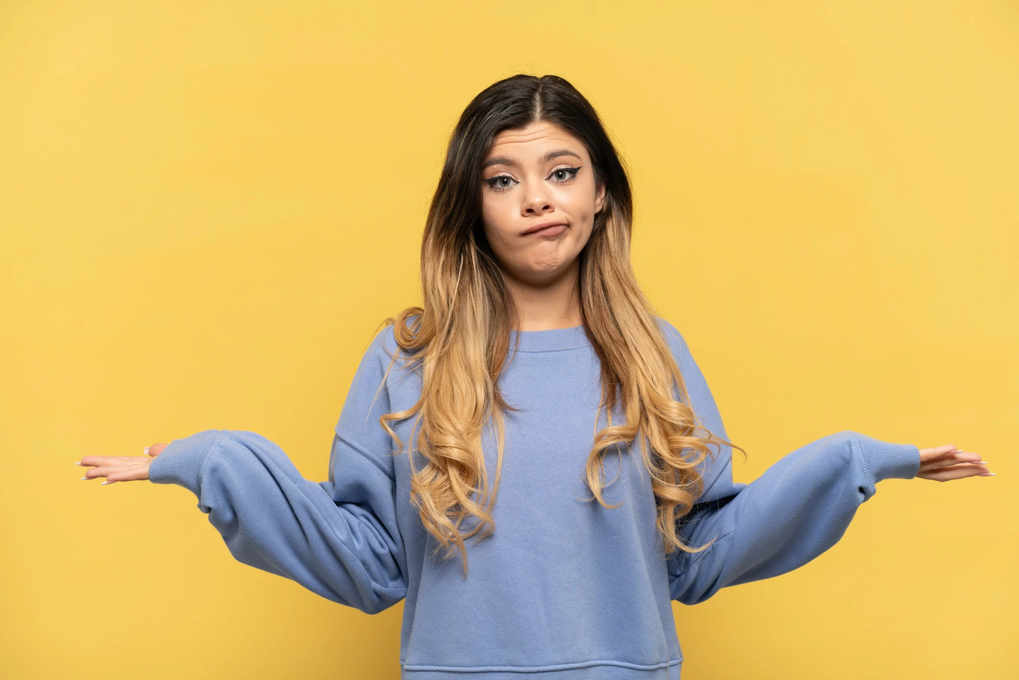 Young Russian girl isolated on yellow background having doubts while raising hands