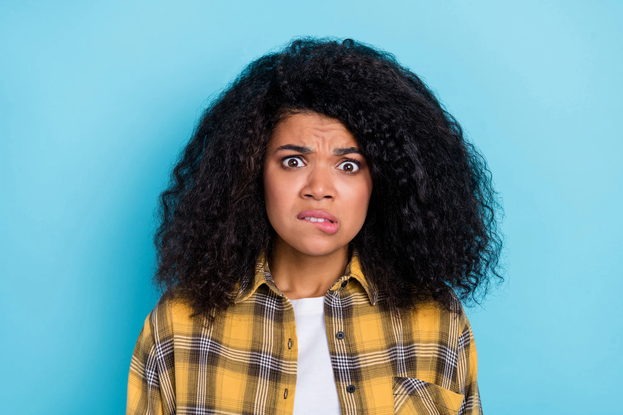 Photo of nervous scared lady bite lip watch horror movie moment wear plaid shirt isolated blue color background.