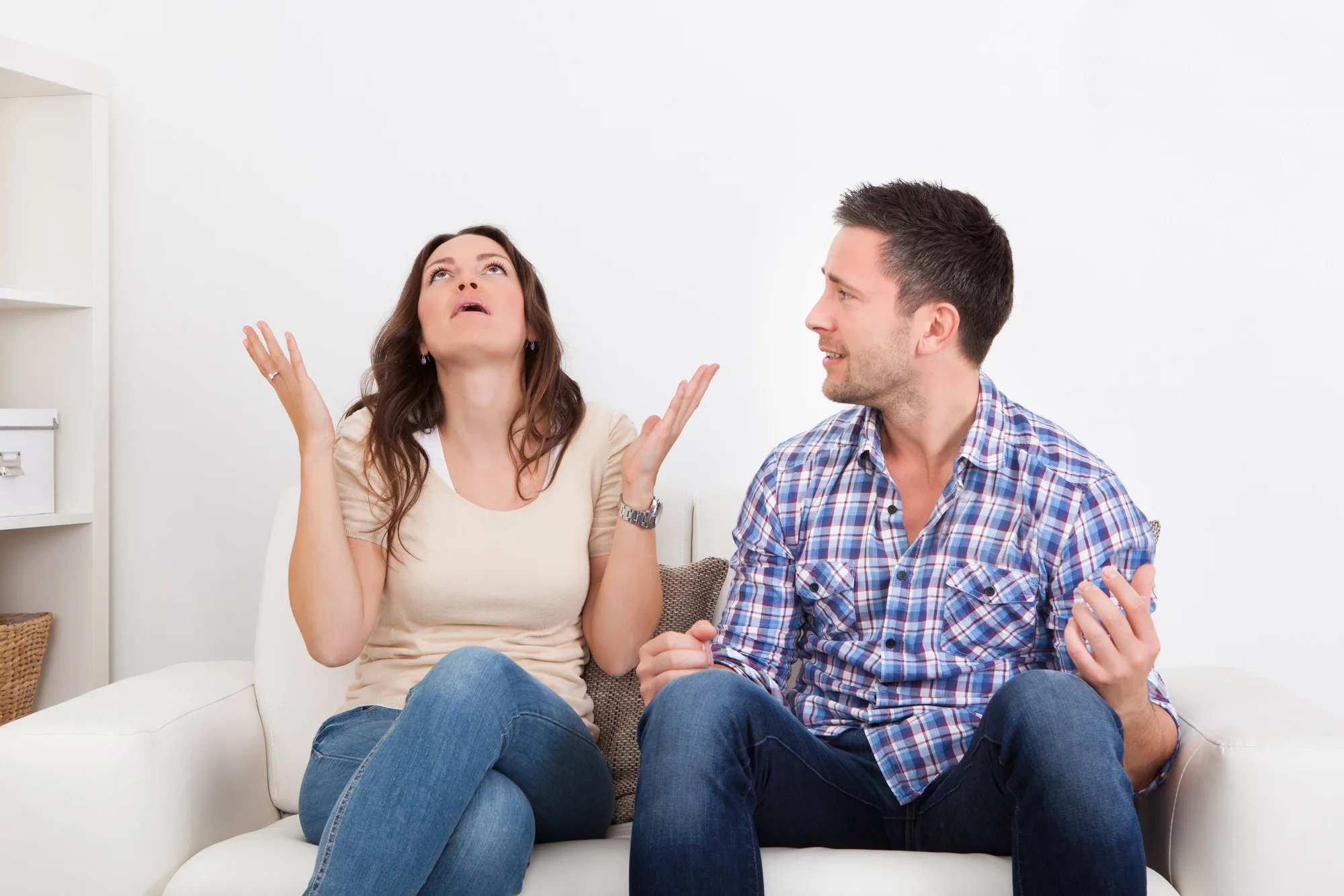 Portrait Of Frustrated Couple Sitting On Couch Quarreling With Each Other