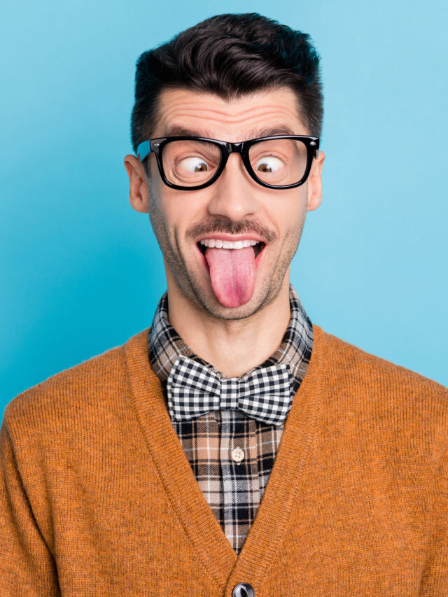 Photo of crazy funny young nerdy man stick tongue out fooling face joke isolated on blue color background.