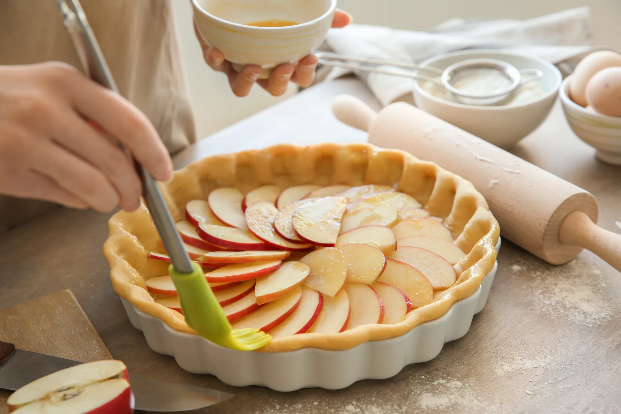 Woman preparing apple pie at table