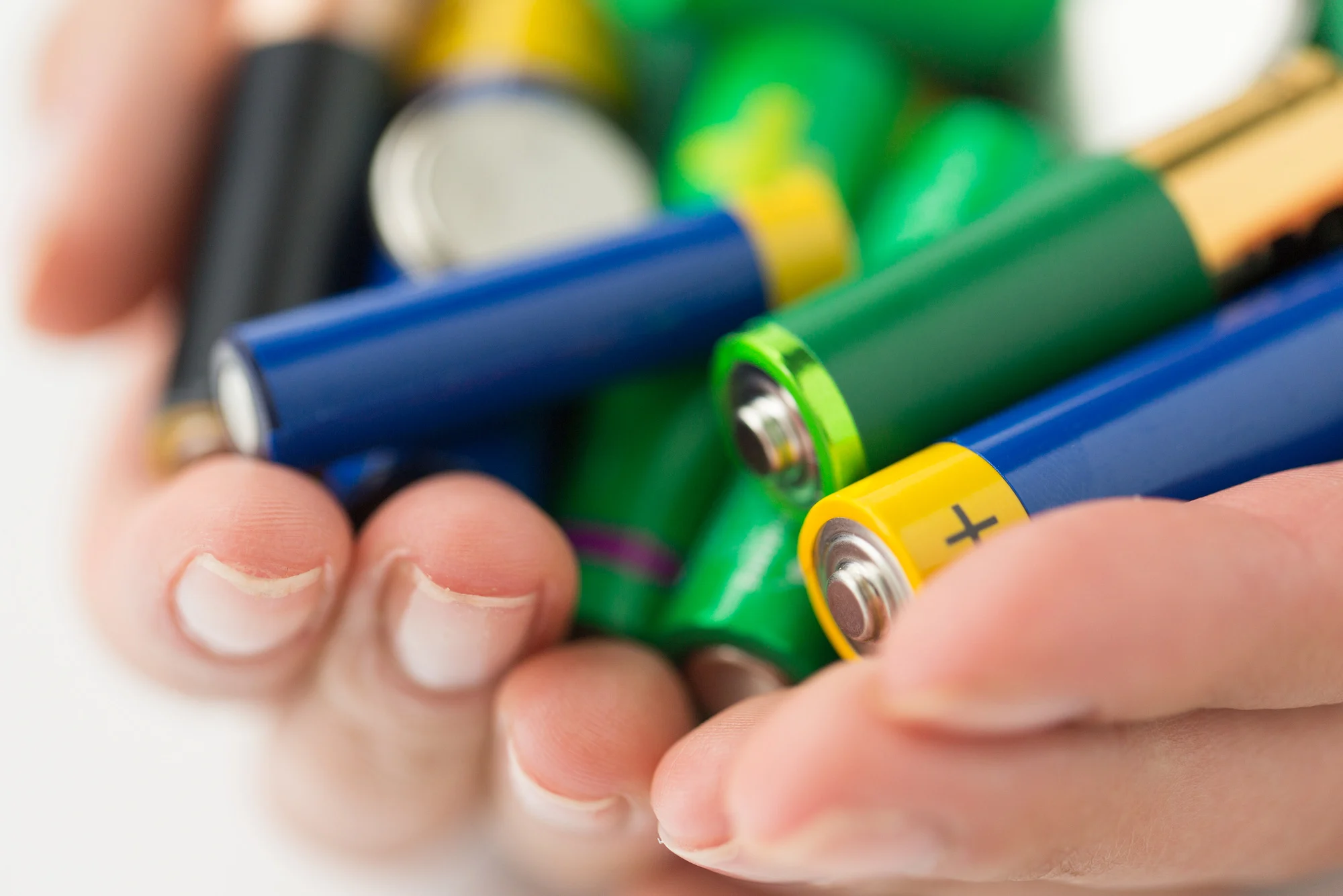 recycling, energy, power, environment and ecology concept - close up of hands holding alkaline batteries heap